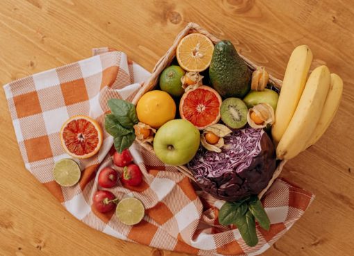 A vibrant flat lay of assorted fresh fruits on a checkered cloth over a wooden surface, perfect for healthy lifestyle concepts.